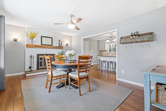 11 Beauchesne Dr, Hooksett, NH 03106 - dining room with wood finished floors, ceiling fan, a brick fireplace, a textured ceiling, and baseboards
