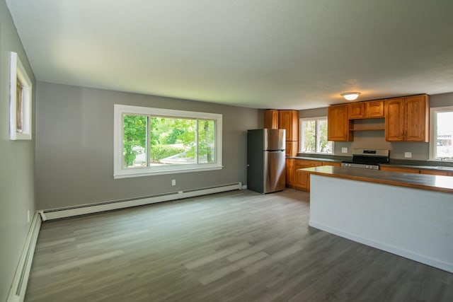 82 S Jewett St, Manchester, NH 03103 - kitchen featuring appliances with stainless steel finishes, a baseboard radiator, wood finished floors, brown cabinets, and dark countertops