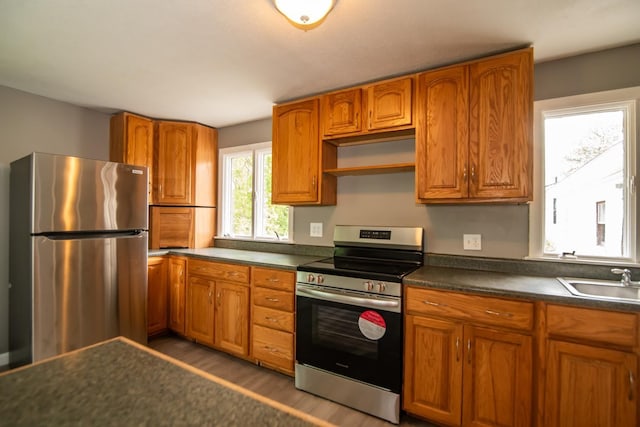 82 S Jewett St, Manchester, NH 03103 - kitchen featuring appliances with stainless steel finishes, a sink, light wood finished floors, dark countertops, and brown cabinetry