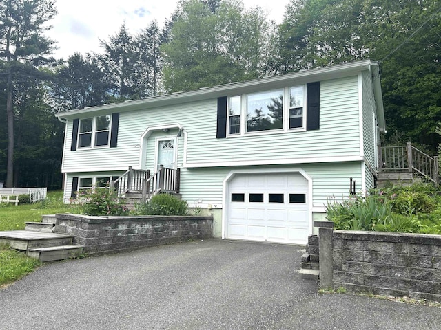 34 Hampshire Cir, Brattleboro, VT 05301 - bi-level home featuring an attached garage, driveway, and view of wooded area