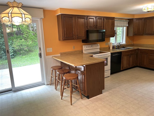 34 Hampshire Cir, Brattleboro, VT 05301 - kitchen with black appliances, a sink, wainscoting, a peninsula, and a breakfast bar area