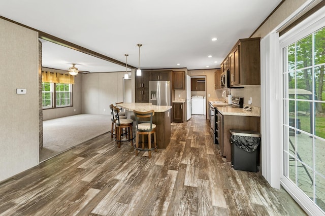 29 Stoneham Rd Unit 4, Wakefield, NH 03872 - kitchen featuring stainless steel appliances, washer / clothes dryer, dark wood finished floors, a kitchen island, and a breakfast bar