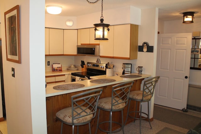 16 Penstock Rd Unit 4, Lincoln, NH 03251 - kitchen with appliances with stainless steel finishes, light countertops, a breakfast bar area, a peninsula, and pendant lighting