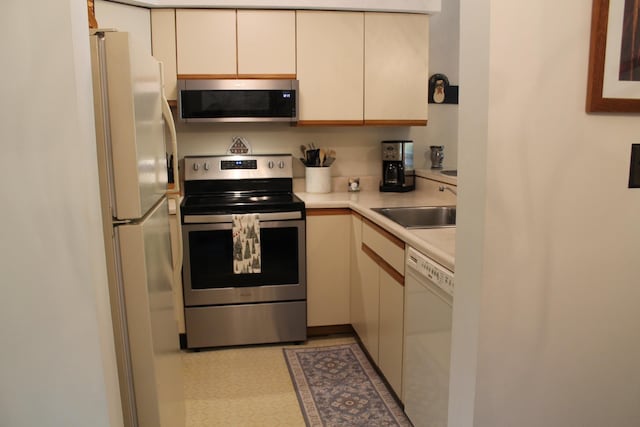 16 Penstock Rd Unit 4, Lincoln, NH 03251 - kitchen with appliances with stainless steel finishes, a sink, light countertops, light floors, and cream cabinetry