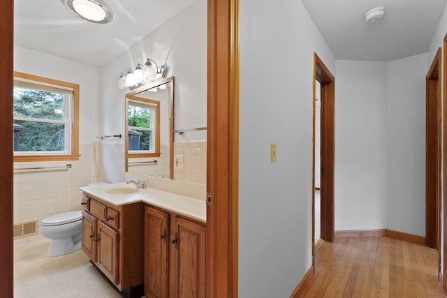 33 Wildwood Dr, Burlington, VT 05408 - half bath featuring toilet, vanity, tile walls, hardwood / wood-style floors, and wainscoting
