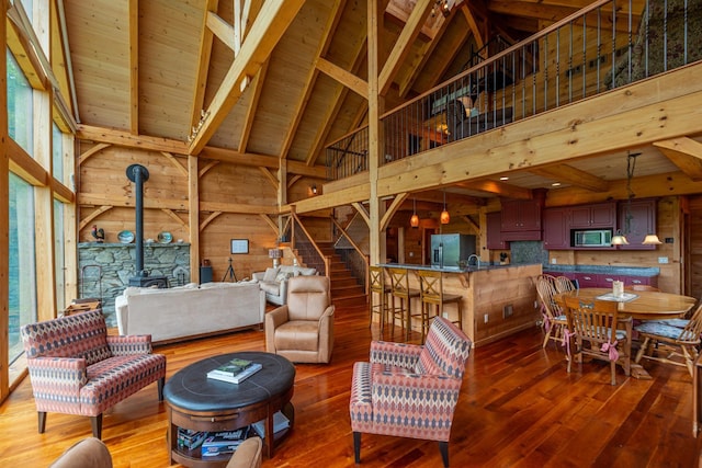 938 Stigers Rd, Andover, VT 05143 - living area featuring a wood stove, high vaulted ceiling, wood walls, hardwood / wood-style flooring, and stairs