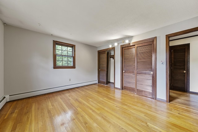 3 Timber Ln, Merrimack, NH 03054 - unfurnished bedroom with light wood finished floors, multiple closets, baseboards, and a baseboard radiator