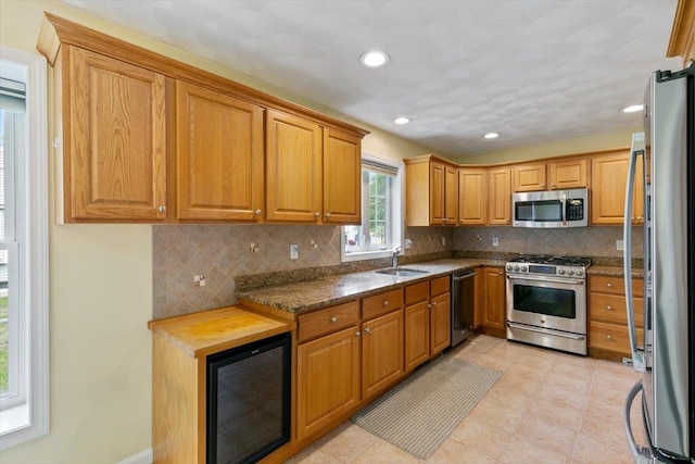 10 Hadleigh Rd, Windham, NH 03087 - kitchen featuring appliances with stainless steel finishes, beverage cooler, backsplash, a sink, and brown cabinets