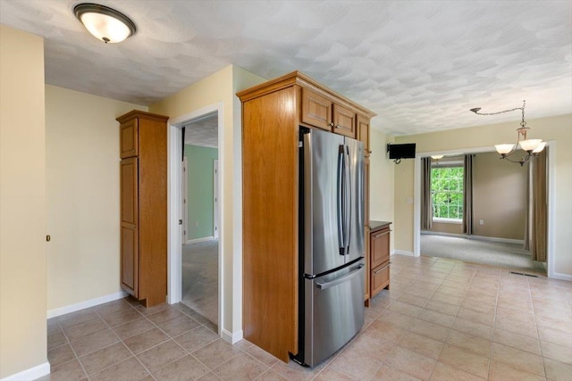 10 Hadleigh Rd, Windham, NH 03087 - kitchen with freestanding refrigerator, a chandelier, a textured ceiling, brown cabinetry, and light tile patterned floors