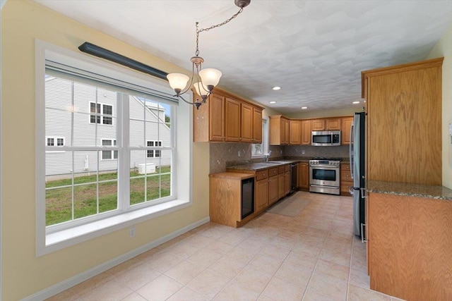 10 Hadleigh Rd, Windham, NH 03087 - kitchen with appliances with stainless steel finishes, brown cabinetry, a chandelier, tasteful backsplash, and baseboards