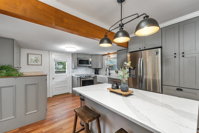 47 Foch St, Manchester, NH 03104 - kitchen with stainless steel appliances, gray cabinetry, light wood-type flooring, a kitchen breakfast bar, and light stone countertops