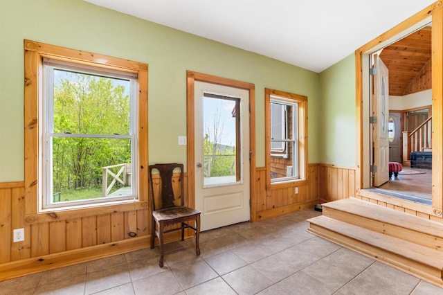 174 Sky View Rd, Stratford, NH 03590 - doorway featuring wainscoting, healthy amount of natural light, wooden walls, tile patterned flooring, and stairs