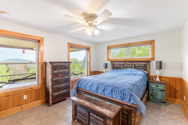 174 Sky View Rd, Stratford, NH 03590 - bedroom with multiple windows, a wainscoted wall, wooden walls, light tile patterned floors, and ceiling fan