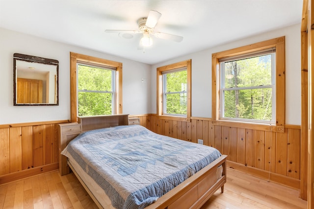 174 Sky View Rd, Stratford, NH 03590 - bedroom featuring wainscoting, wooden walls, light wood-style floors, and ceiling fan