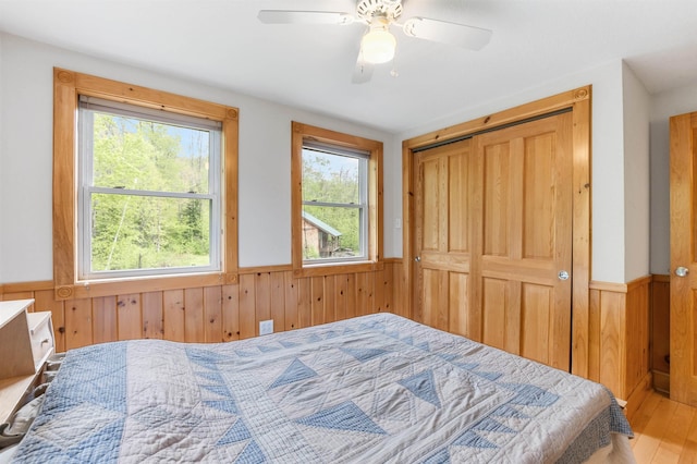 174 Sky View Rd, Stratford, NH 03590 - bedroom with wainscoting, wooden walls, wood finished floors, a closet, and ceiling fan
