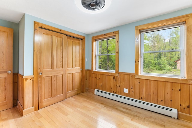 174 Sky View Rd, Stratford, NH 03590 - unfurnished bedroom with a baseboard radiator, a wainscoted wall, light wood finished floors, wood walls, and a closet