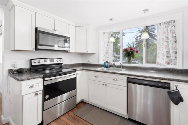 19 Overland St, Laconia, NH 03246 - kitchen with appliances with stainless steel finishes, a sink, dark countertops, white cabinetry, and dark wood finished floors