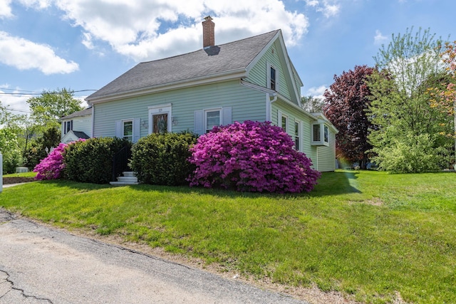 129 Indigo Hill Rd, Somersworth, NH 03878 - view of home's exterior with a chimney, a yard, and roof with shingles
