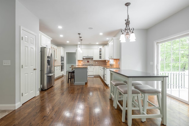 35 Northland Rd, Windham, NH 03087 - kitchen with stainless steel appliances, under cabinet range hood, a breakfast bar area, backsplash, and a kitchen island