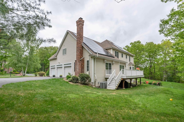 35 Northland Rd, Windham, NH 03087 - view of side of home with an attached garage, a chimney, central AC unit, a wooden deck, and asphalt driveway