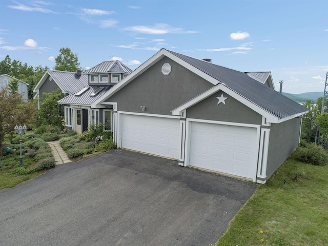 128 Fuller Dr, Canaan, VT 05903 - view of front of home featuring metal roof, a standing seam roof, asphalt driveway, an attached garage, and stucco siding