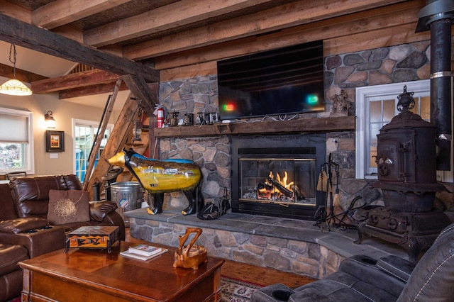 5 N Main St, Wilmington, VT 05363 - living room featuring a wood stove, beam ceiling, and a stone fireplace