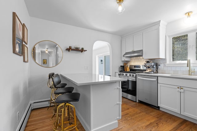 7 Lamson Ln, Hampton, NH 03842 - kitchen featuring appliances with stainless steel finishes, under cabinet range hood, a sink, a peninsula, and arched walkways