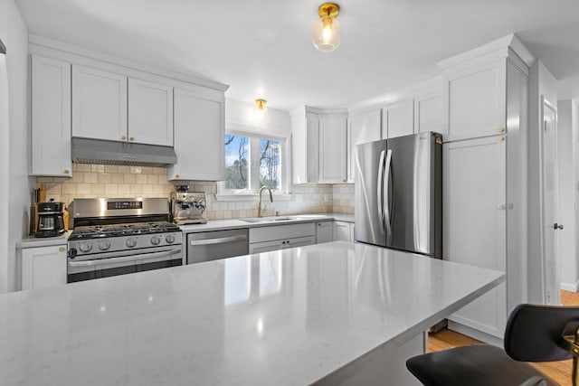 7 Lamson Ln, Hampton, NH 03842 - kitchen featuring stainless steel appliances, under cabinet range hood, a sink, tasteful backsplash, and white cabinetry