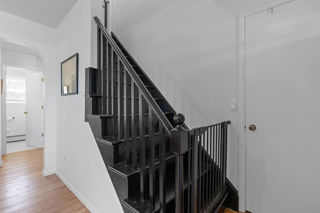 7 Lamson Ln, Hampton, NH 03842 - staircase with arched walkways, wood finished floors, a baseboard heating unit, and baseboards
