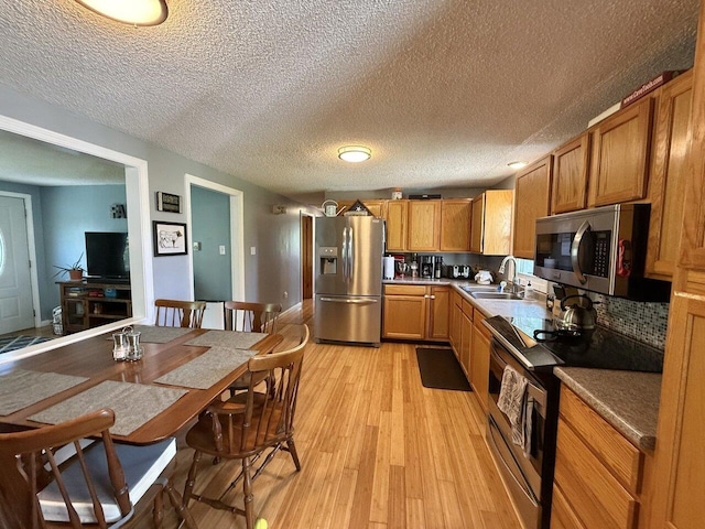50 New Haven Rd, Vergennes, VT 05491 - kitchen featuring stainless steel appliances, a sink, light wood-type flooring, brown cabinetry, and a textured ceiling