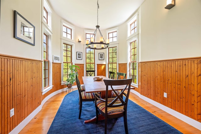 10 Wiswall Hill Rd, Newfane, VT 05345 - dining room featuring a chandelier, a wainscoted wall, hardwood / wood-style floors, wooden walls, and a towering ceiling