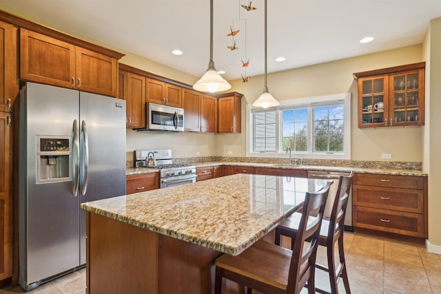 222 Park View Rd, Springfield, VT 05156 - kitchen featuring appliances with stainless steel finishes, a sink, brown cabinetry, a kitchen bar, and light stone countertops