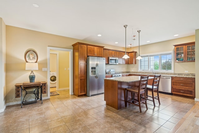 222 Park View Rd, Springfield, VT 05156 - kitchen with appliances with stainless steel finishes, washer / clothes dryer, a kitchen island, brown cabinets, and a breakfast bar