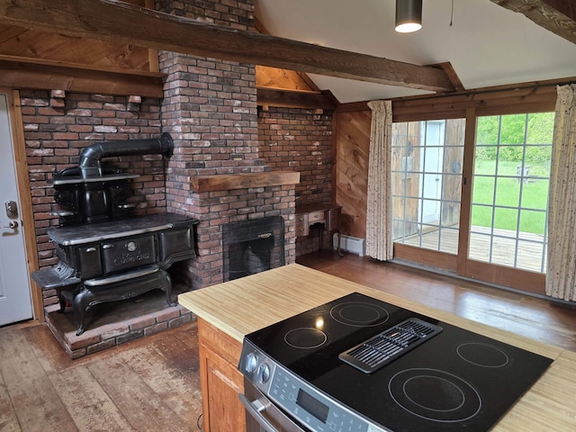 3458 Vt Route 30, Jamaica, VT 05343 - kitchen with stainless steel electric range oven, a wood stove, hardwood / wood-style flooring, beam ceiling, and wood walls