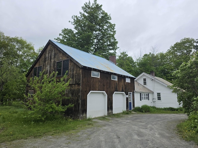 3458 Vt Route 30, Jamaica, VT 05343 - view of front of house with dirt driveway, a chimney, and a detached garage