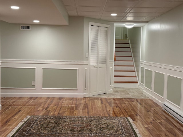 4 Sunblaze Dr, Nashua, NH 03062 - finished basement with a baseboard heating unit, wood finished floors, a decorative wall, a wainscoted wall, and stairway