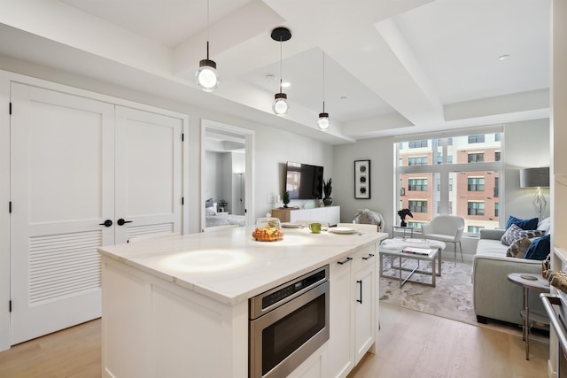 18 Artisan Dr Unit 419, Salem, NH 03079 - kitchen featuring stainless steel microwave, open floor plan, light wood-style floors, and a tray ceiling