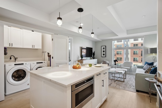 18 Artisan Dr Unit 419, Salem, NH 03079 - kitchen with stainless steel microwave, a tray ceiling, open floor plan, washer and clothes dryer, and light wood-style flooring