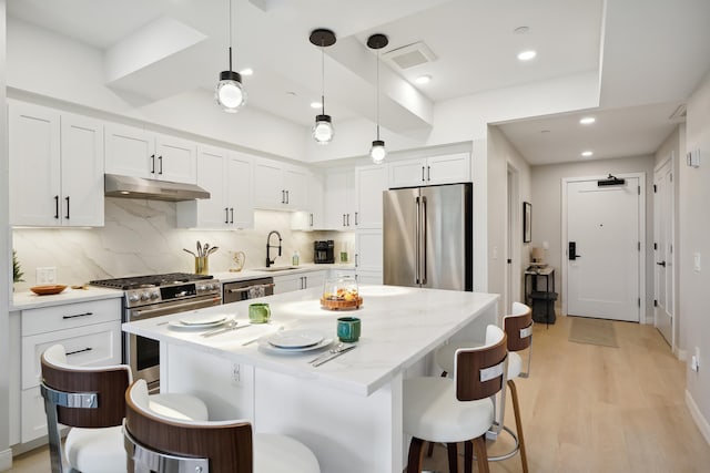 18 Artisan Dr Unit 419, Salem, NH 03079 - kitchen with stainless steel appliances, under cabinet range hood, a sink, a kitchen breakfast bar, and recessed lighting