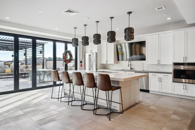 18 Artisan Dr Unit 419, Salem, NH 03079 - kitchen with appliances with stainless steel finishes, a center island, a kitchen breakfast bar, backsplash, and white cabinets
