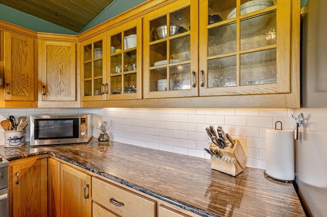 300 River Rd, Enosburg, VT 05450 - kitchen featuring stainless steel microwave, lofted ceiling, tasteful backsplash, brown cabinetry, and glass insert cabinets