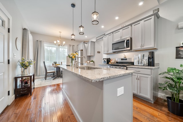 218 Manchester St, Nashua, NH 03064 - kitchen with stainless steel appliances, a sink, hardwood / wood-style flooring, a chandelier, and an island with sink
