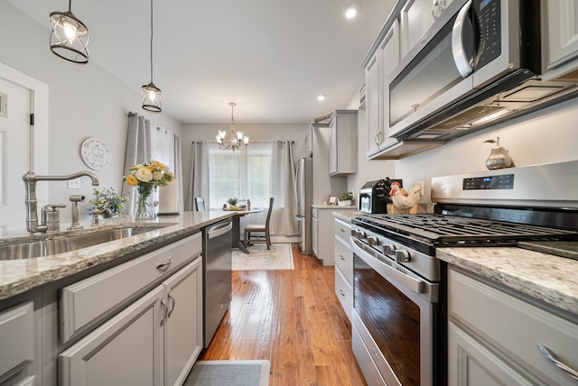 218 Manchester St, Nashua, NH 03064 - kitchen with stainless steel appliances, a sink, a chandelier, and hanging light fixtures