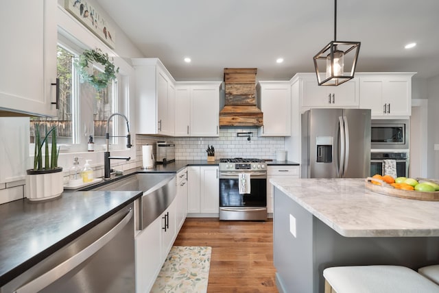218 Manchester St, Nashua, NH 03064 - kitchen featuring stainless steel appliances, custom range hood, a sink, decorative backsplash, and white cabinetry