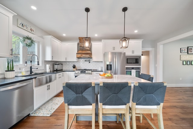 218 Manchester St, Nashua, NH 03064 - kitchen featuring appliances with stainless steel finishes, custom exhaust hood, a sink, decorative backsplash, and a kitchen bar