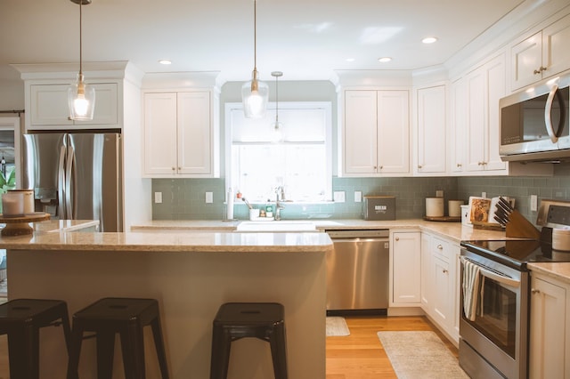 7 Plum St, Concord, NH 03301 - kitchen with appliances with stainless steel finishes, a sink, a breakfast bar, white cabinetry, and recessed lighting