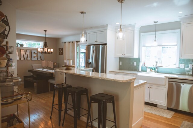 7 Plum St, Concord, NH 03301 - kitchen featuring stainless steel appliances, light wood-style floors, decorative backsplash, a center island, and a breakfast bar area