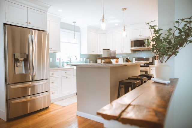 7 Plum St, Concord, NH 03301 - kitchen featuring stainless steel appliances, white cabinets, decorative backsplash, light wood-style flooring, and recessed lighting