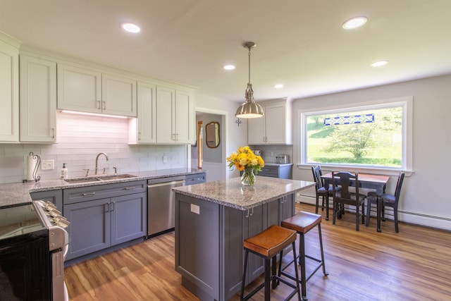 2147 Vt Route 111, Derby, VT 05829 - kitchen featuring a sink, stainless steel dishwasher, light wood-style floors, decorative backsplash, and a kitchen bar