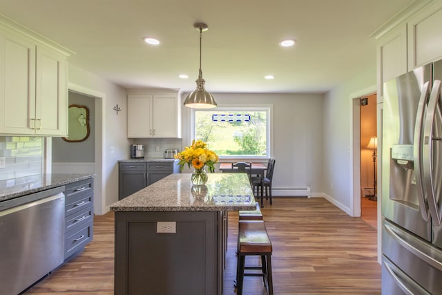 2147 Vt Route 111, Derby, VT 05829 - kitchen with stainless steel appliances, wood finished floors, a breakfast bar, a baseboard radiator, and recessed lighting